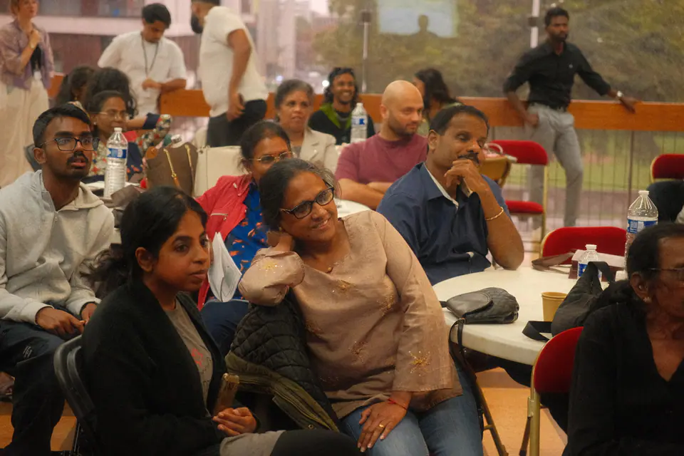Des participant·es de tous âges écoutent attentivement une intervention, assis autour des tables
